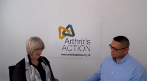 Image of Martin and Heather talking with an Arthritis Action poster on the wall.
