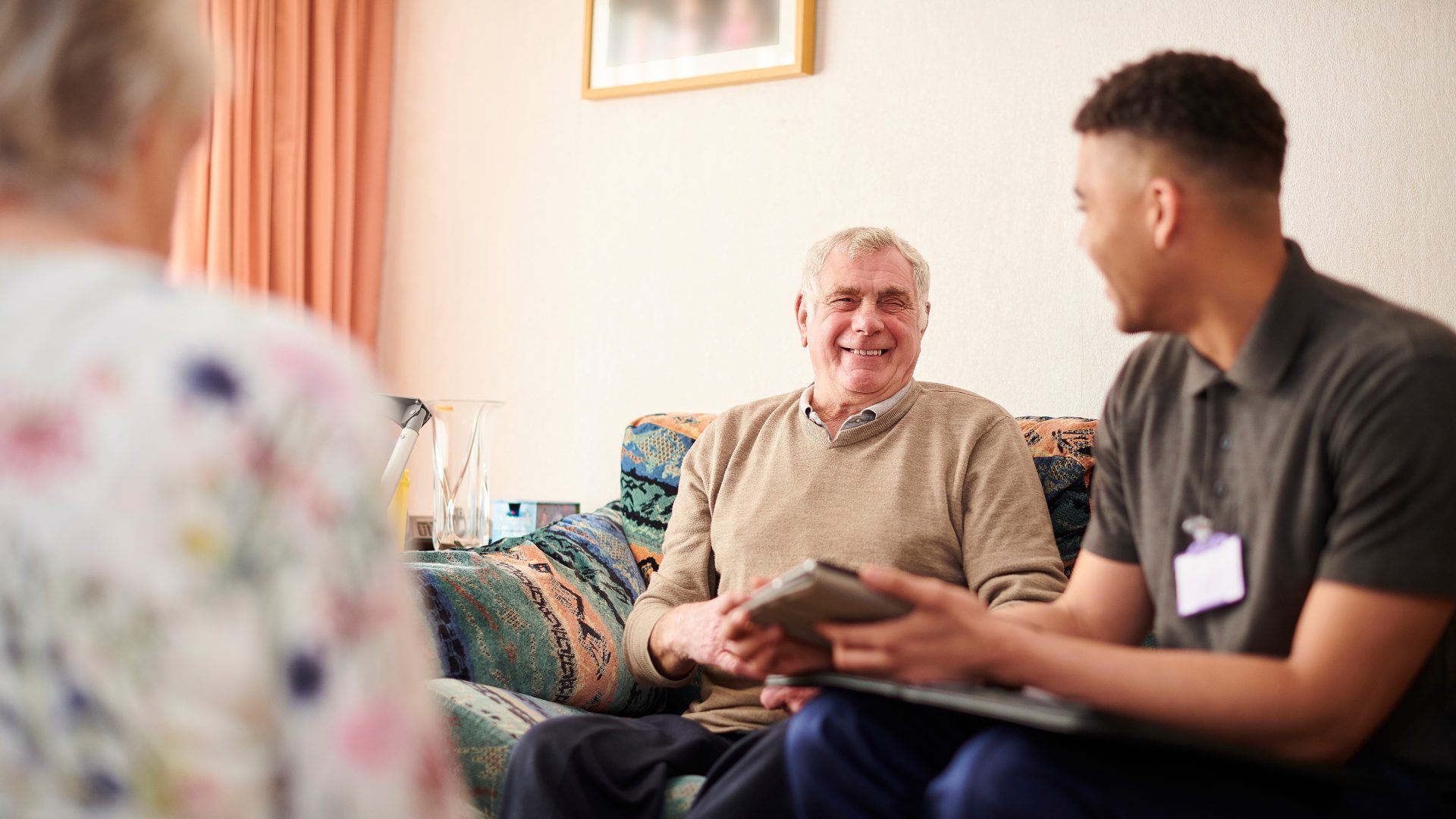 Man sits supporting an older couple in their home
